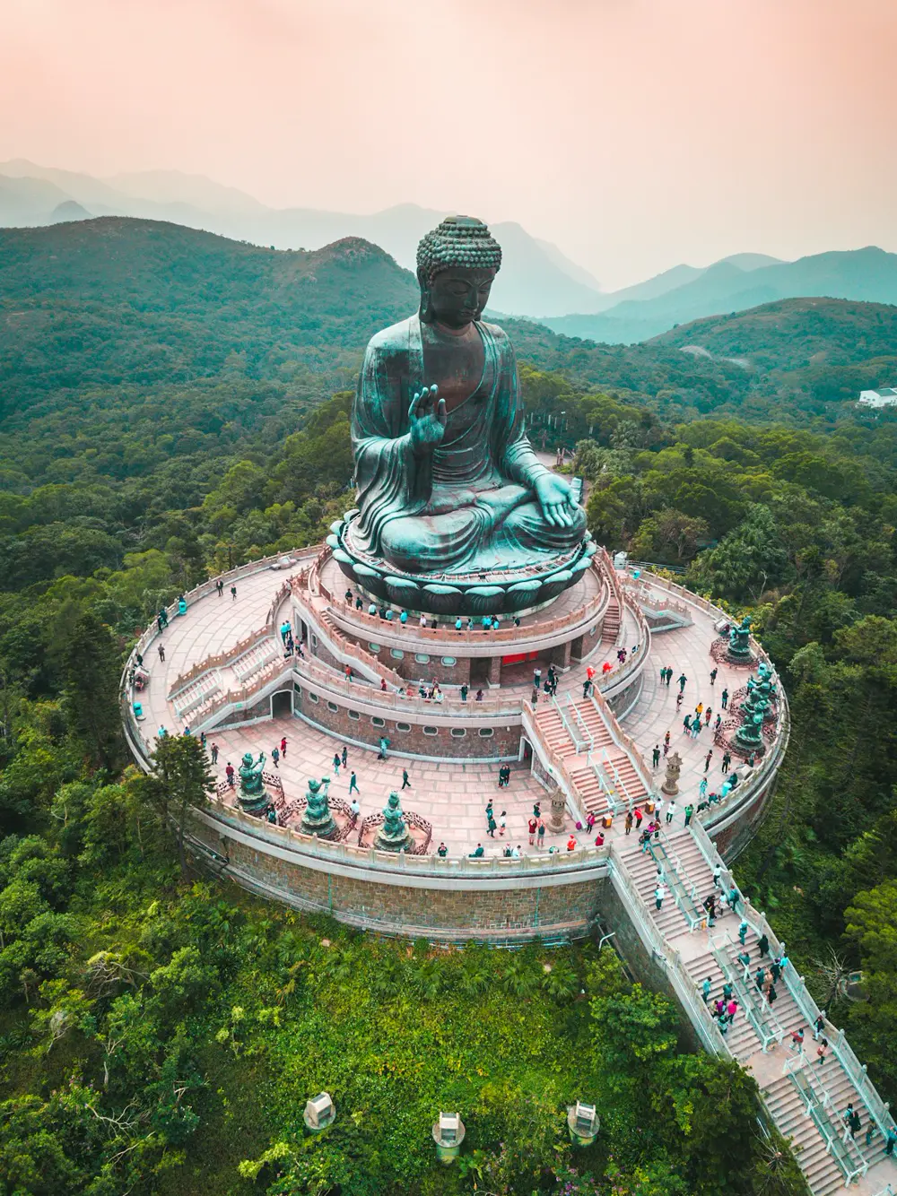 山间平台上的巨型青铜佛像，周围有台阶与游客